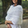 Handcrafted white knitted poncho with elegant drape and detailed pattern texture